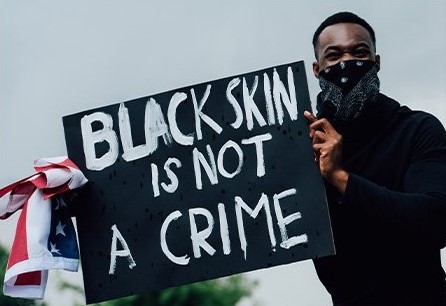 Man holding sign saying "Black skin is not a crime."