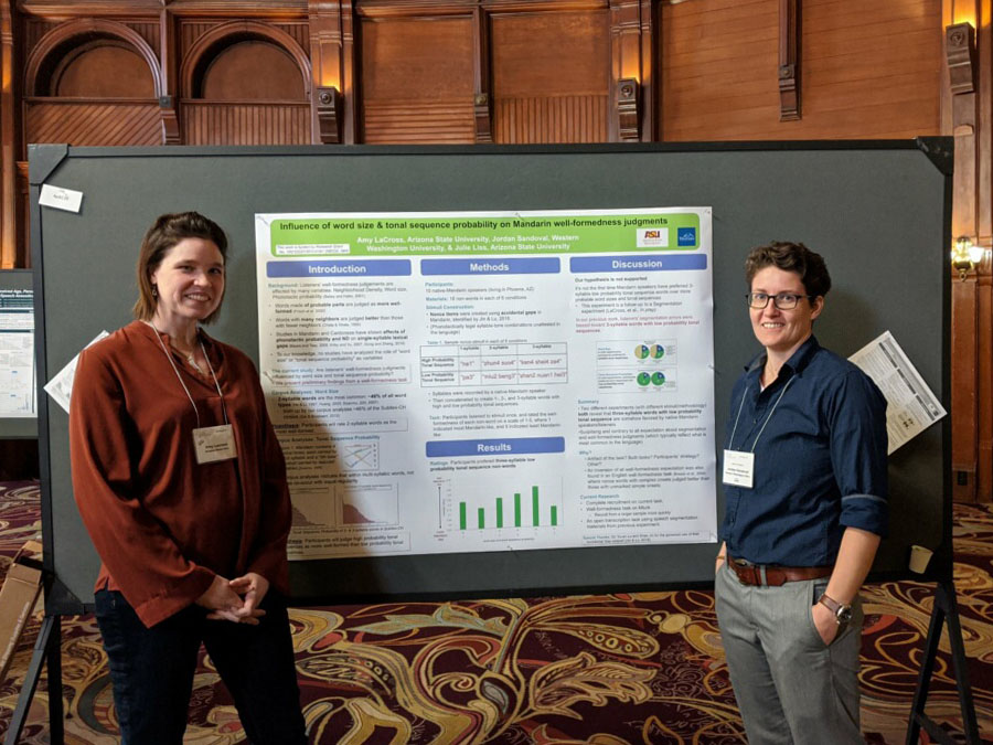 Dr. Amy Lacross and Dr. Jordon Sandoval pose in front of a scientific poster