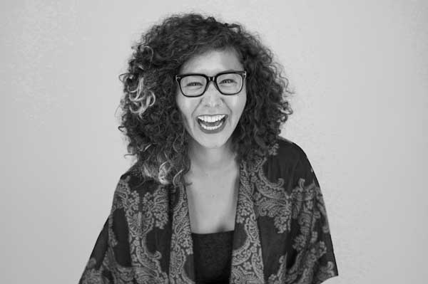Woman with a colorful tunic and glasses laughs for the camera