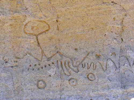 Detailed petroglyphs on rock, with various circles, dots, and squiggles
