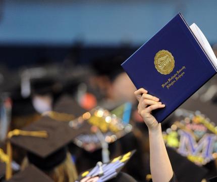 Student holding diploma cover at Western Washintgon University commencement ceremony.