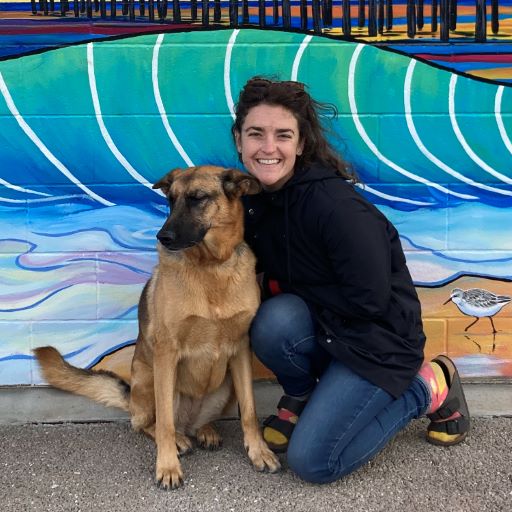 Elizabeth with her dog in front of a mural of the ocean pier