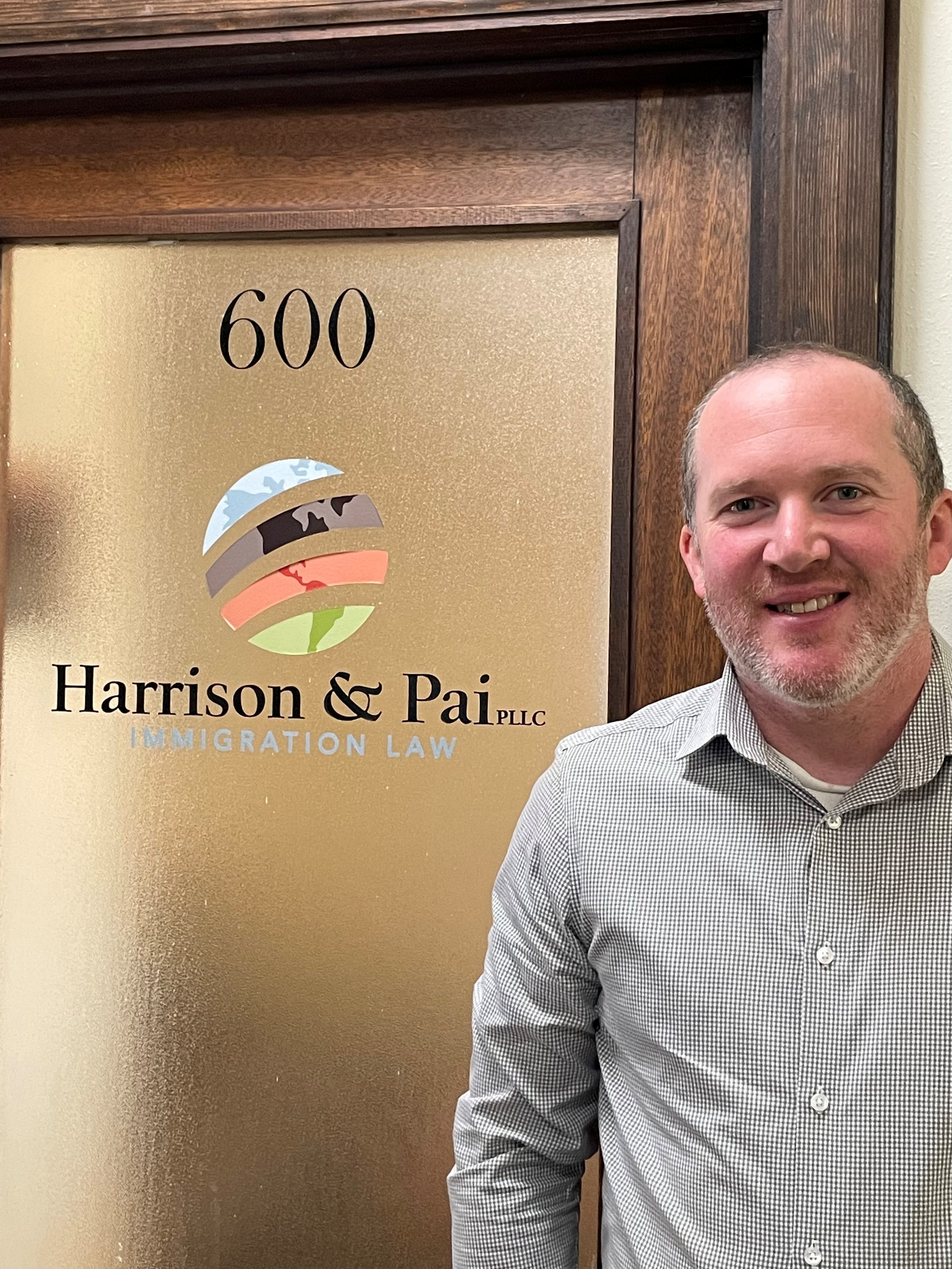 Gabriel Harrison, a white man, standing in front of a door labeled "Harrison & Pai." This is the door to his law firm.