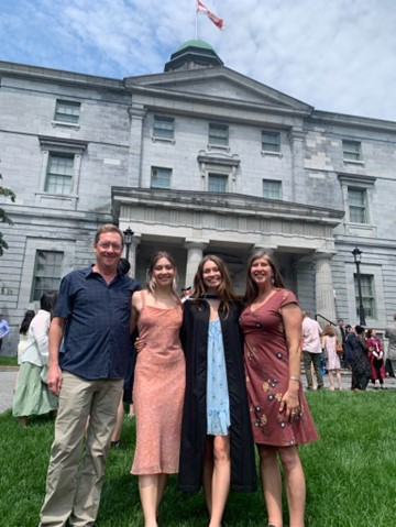 Keith, Sheri and daughters, Alena and Maysee, smiling and standing in front of McGill University building at graduation