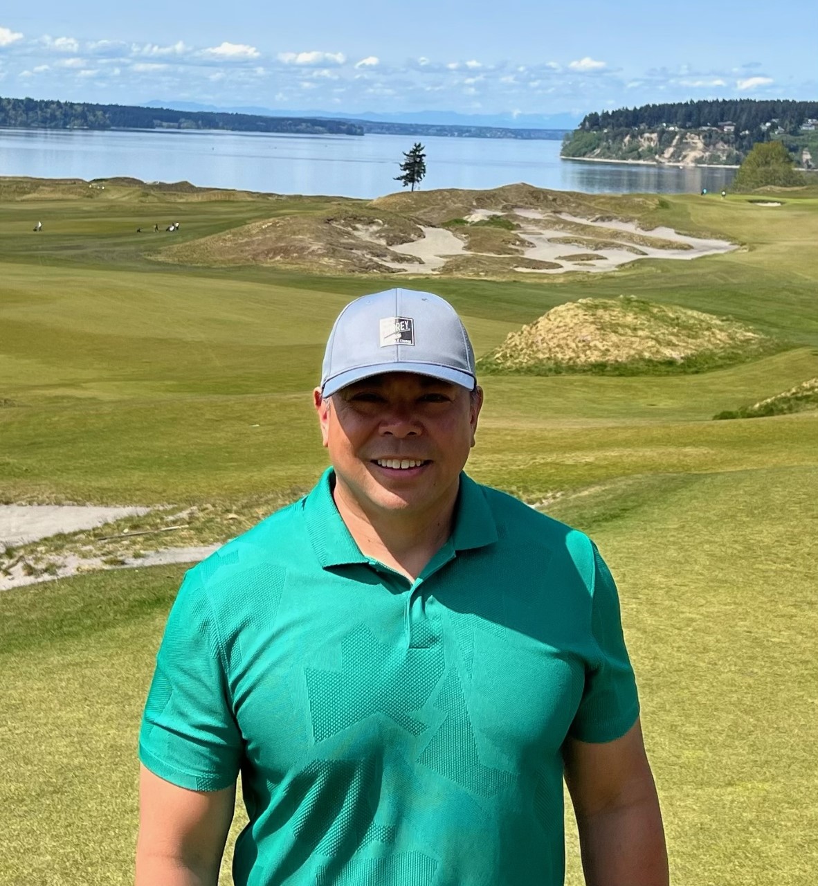 Smiling man in green shirt at Golf course with an ocean view behind him