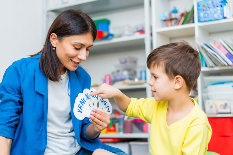 A speech pathologist watches as a child picks out cards with the appropriate letters  on them.
