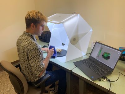 Jack 3D scanning a primate sample next to a laptop 