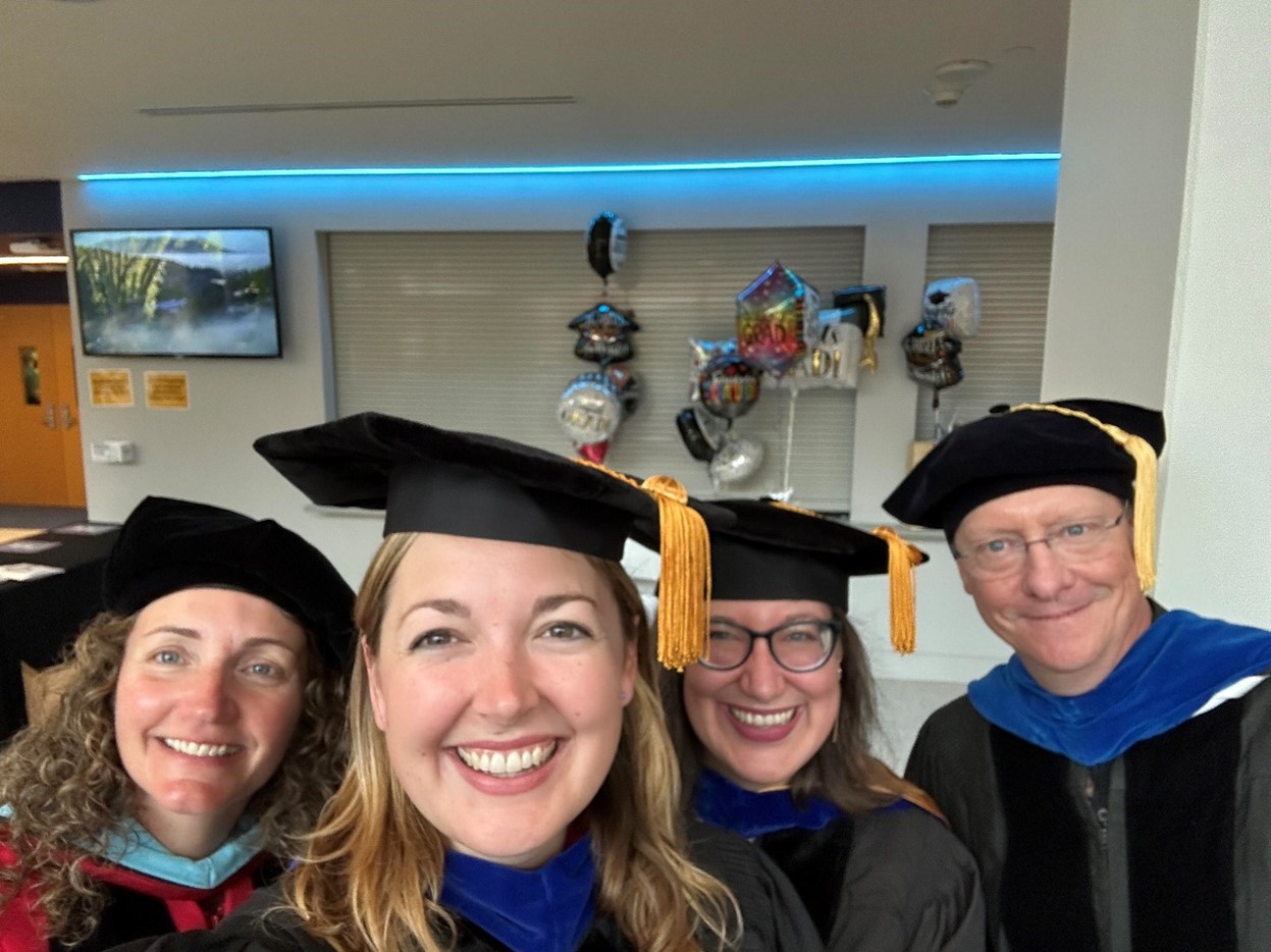 Jessyca, Mary, Kristen and Keith in a cap and gown taking a selfie