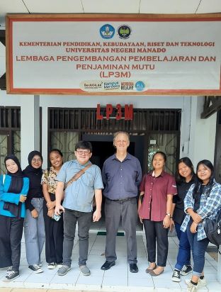 Group photo with a collaborator and students standing in front of a building at Manado State University Tomohon, Indonesia
