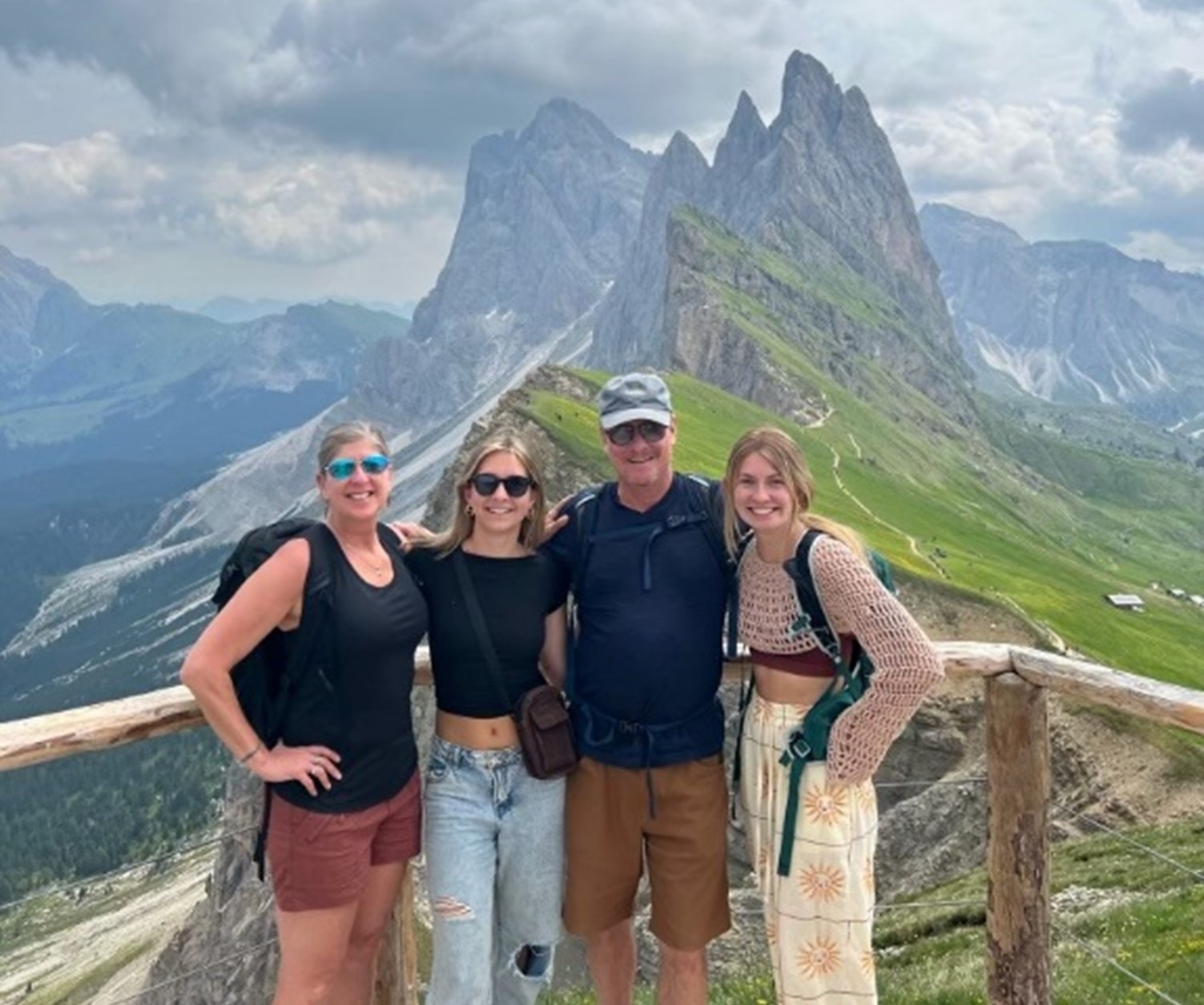 Keith with two daughters and wife standing in from of mountains smiling