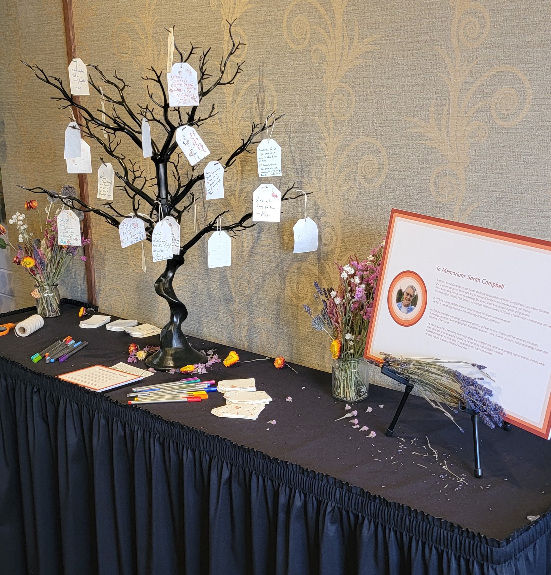 The beautiful memorial table arranged for the late Professor Emerita Sarah Campbell at the 77th Annual Northwest Archaeological Conference of 2024, laden with handwritten notes entailing beloved memories of Sarah. 