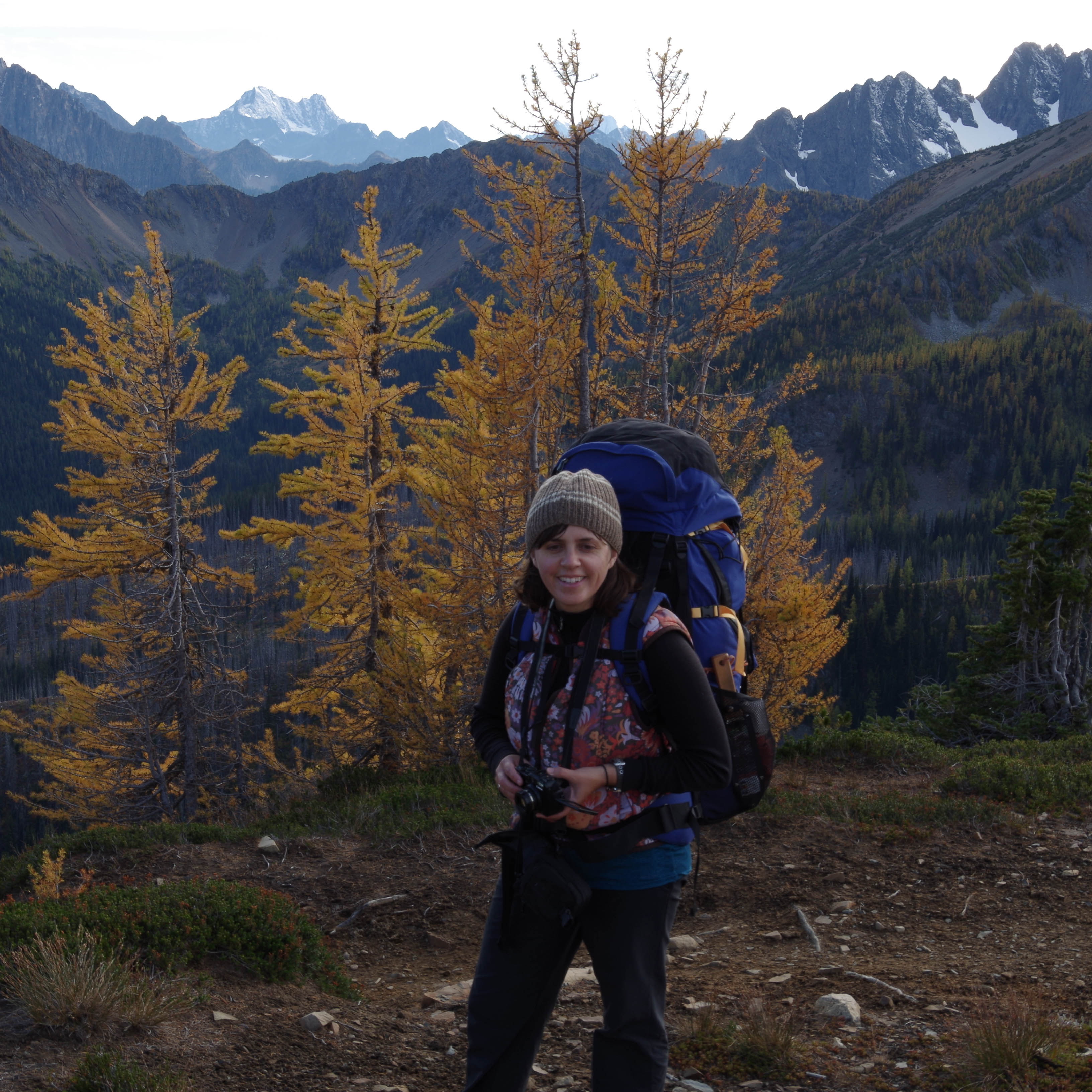 Kirsten Drickey outside, hiking along a trail with mountains and trees in background