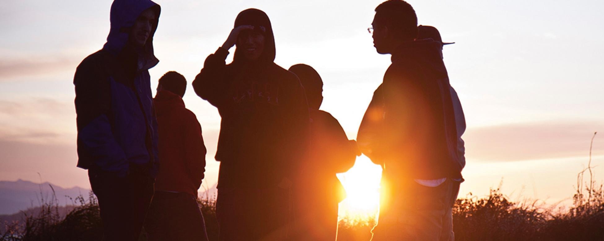 students stand in front of the sunrise in track suits and workout gear