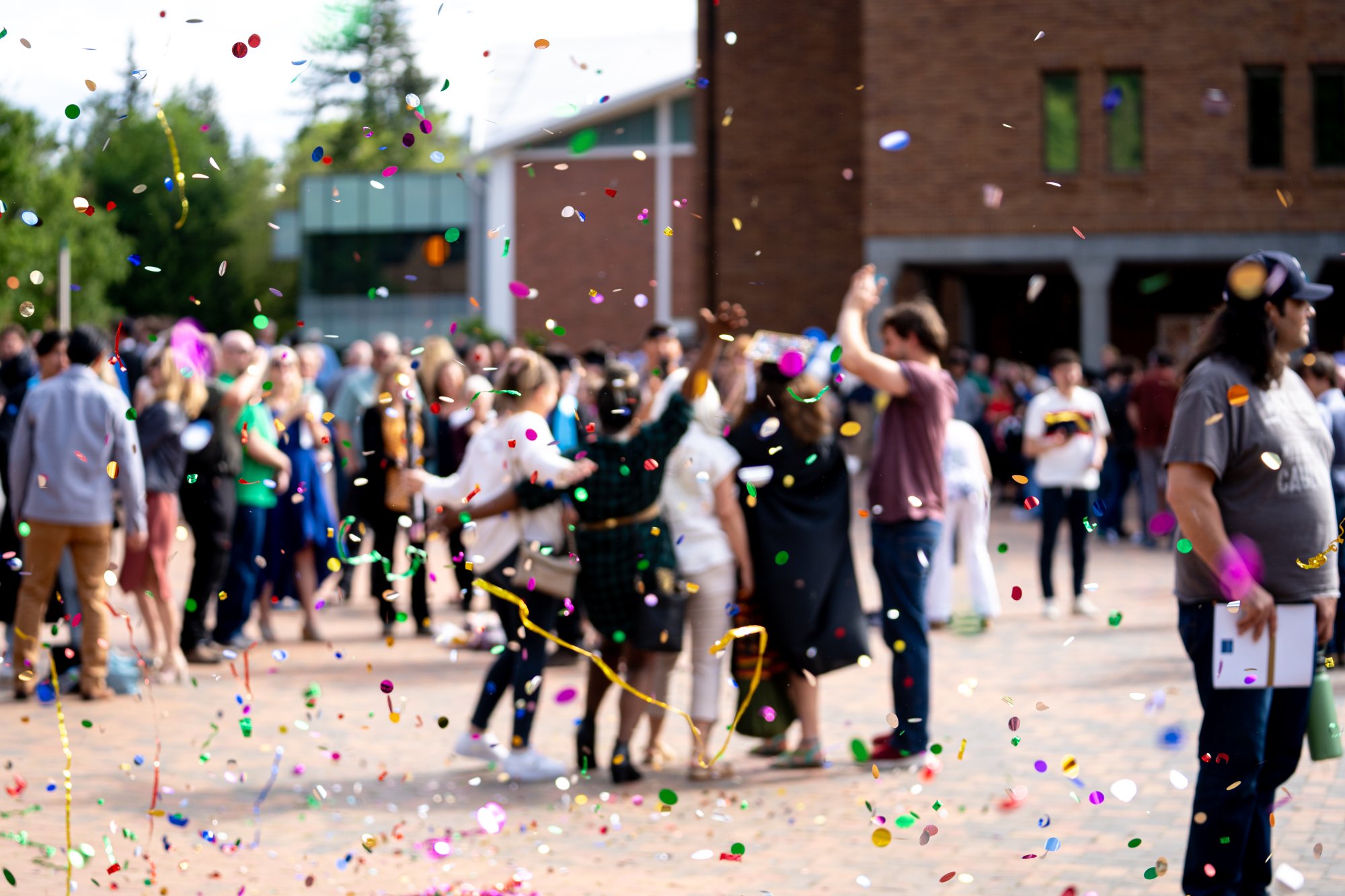 A crowd of graduates outside Bond Hall with confetti in the air.