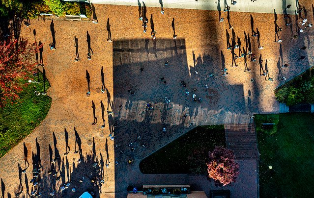 drone shot of students and their shadows walking on red square 