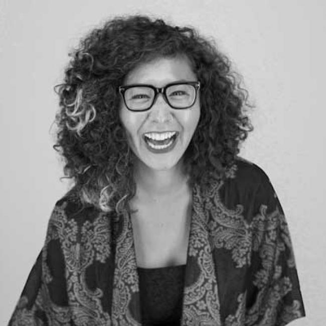 Woman with a colorful tunic and glasses laughs for the camera