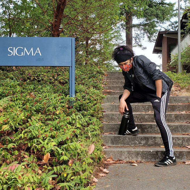 Linguistics major Yukaiya Nomoto posing near the Ridgeway Sigma building sign at Western Washington University.