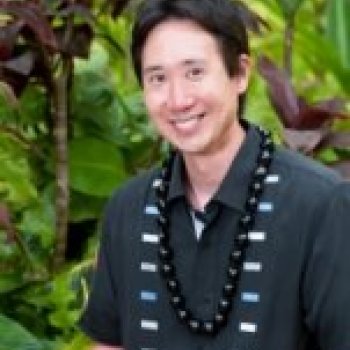Professor Glen Tsunokai standing in front of tropical plants.