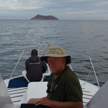 Dr Boxberger on the bow of a sailboat in the ocean approaching an island