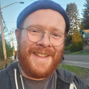 Bearded red-headed man smiling at sunset walking through neighborhood.