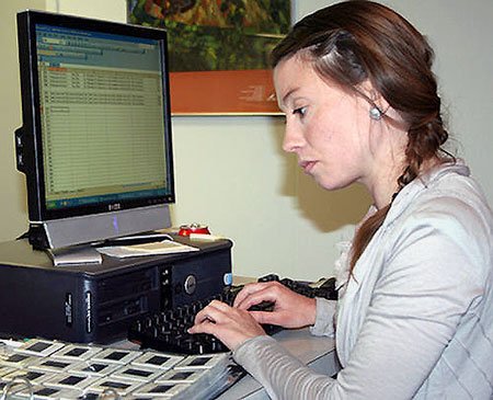 A student works at data entry, entering slide titles on a computer.