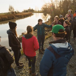 group of faculty and staff stand along a waterway