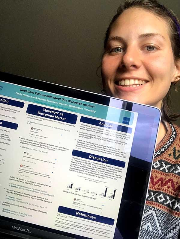 Emily Hillman smiles next to a tablet displaying her research