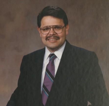 Larry Estrada in black suit and purple striped tie