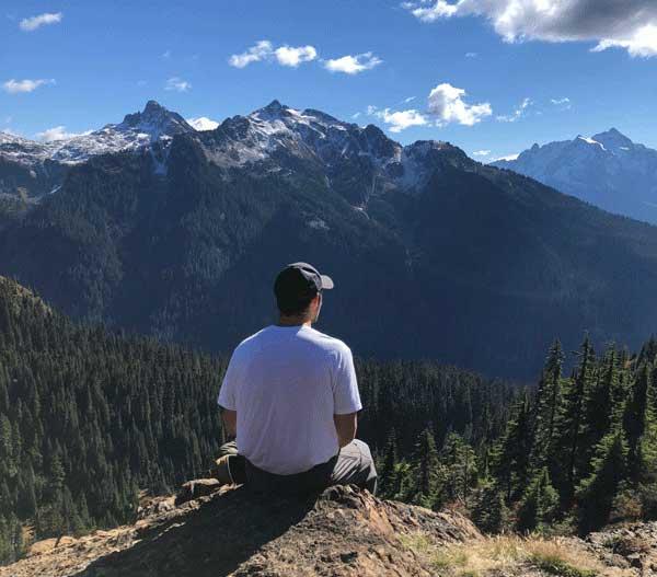 Student sitting on ledge looking at mountain