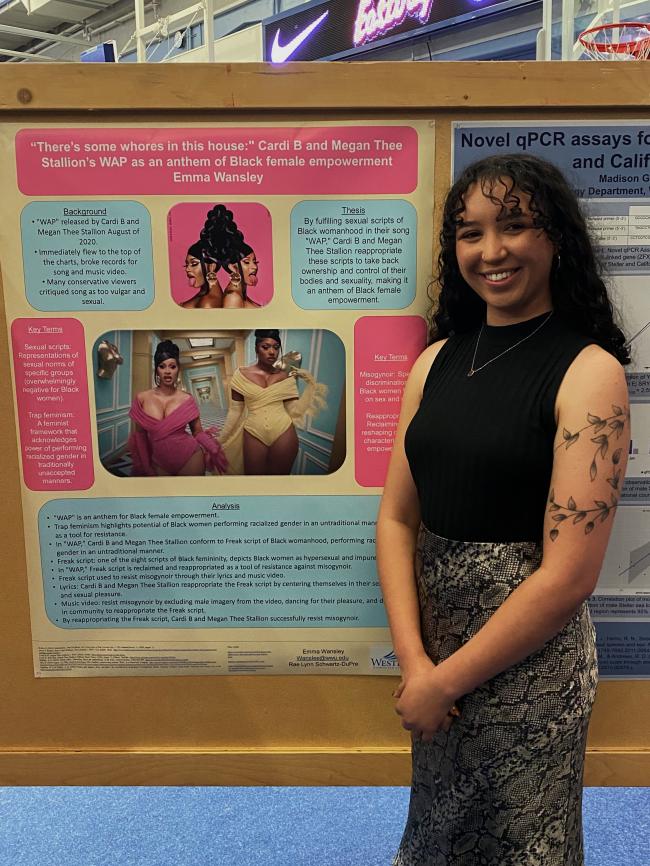 Emma Wansley stands next to her poster on "Trap Feminism and Black Female Empowerment" during scholars week.