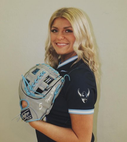 Blonde woman smiling at camera wearing a softball glove