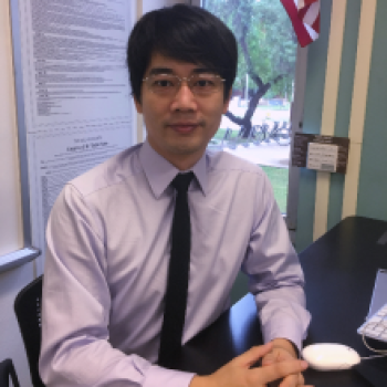 Prof. Julian Siyuan Wu sitting at his desk wearing a button down shirt and tie