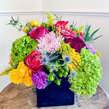 Bouquet of multi-colored flowers in a square blue vase
