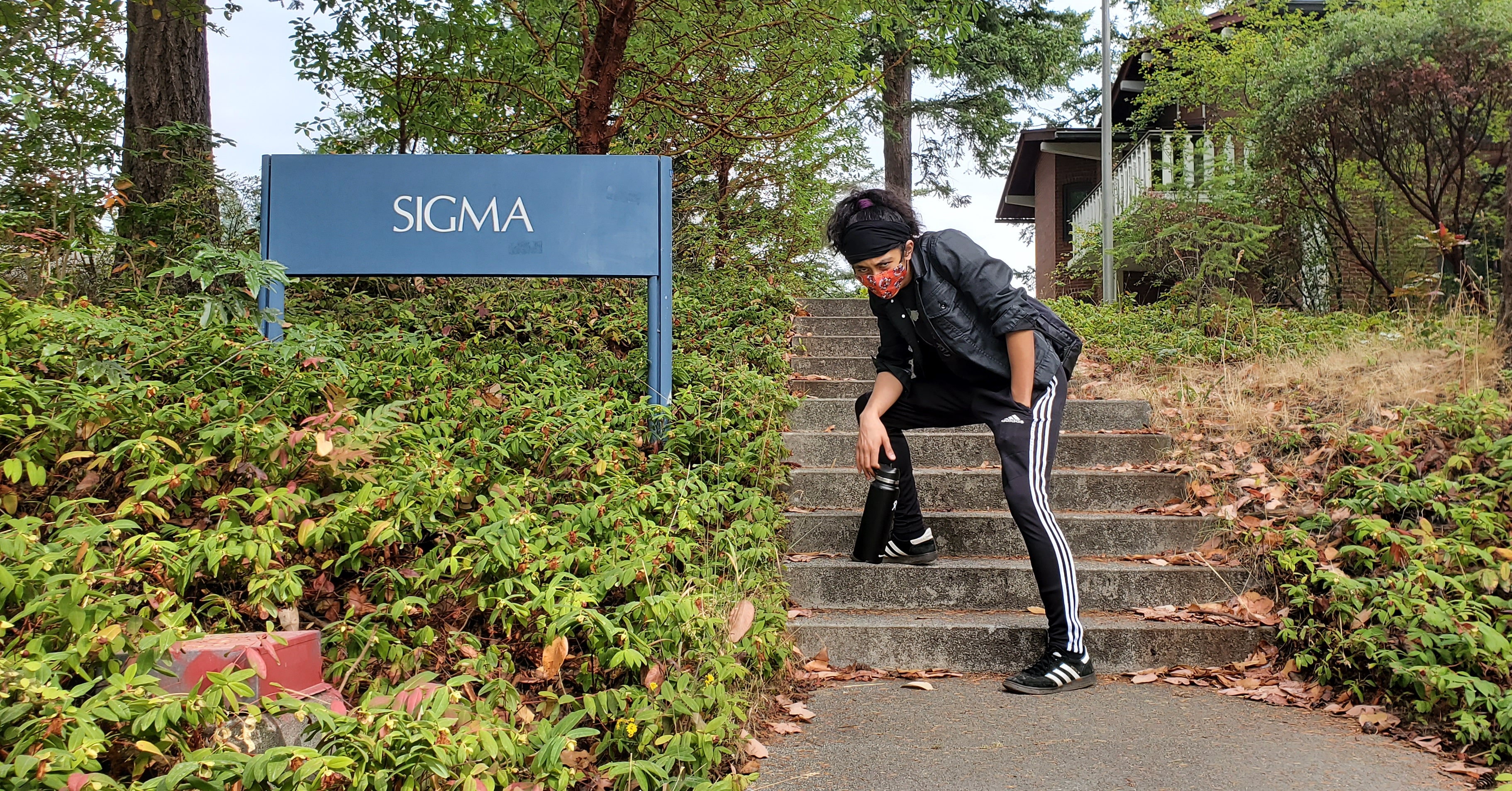Nomoto posing near the Ridgeway Sigma building sign at Western Washington University
