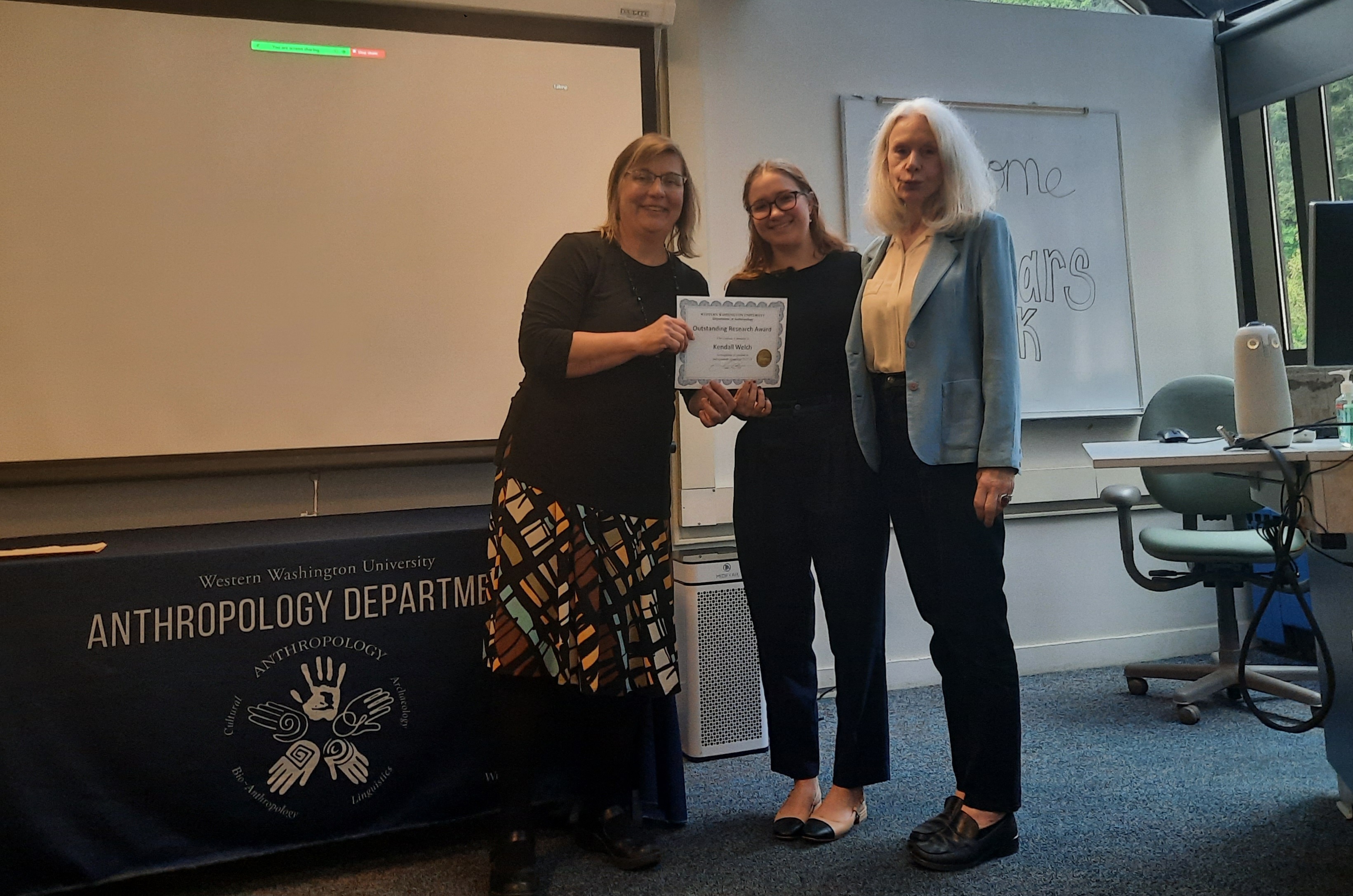 Kendall Welch receiving award from Dr. Judith Pine and Dr. Kathleen Young for Kendall's seminal work titled 'Social Media Warriors: The Use of Social Media as a Weapon in War'.  